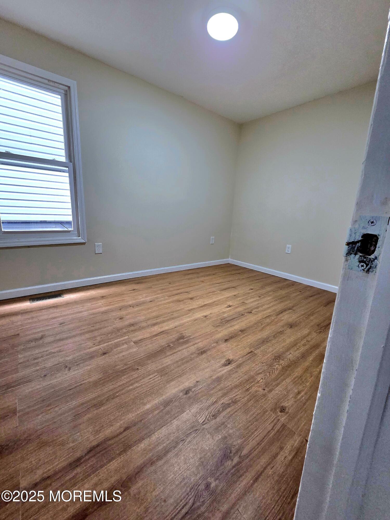 216 Delaware Street Elizabeth Port, NJ 07206 - Photo 23 of 40 an empty room with wooden floor and windows