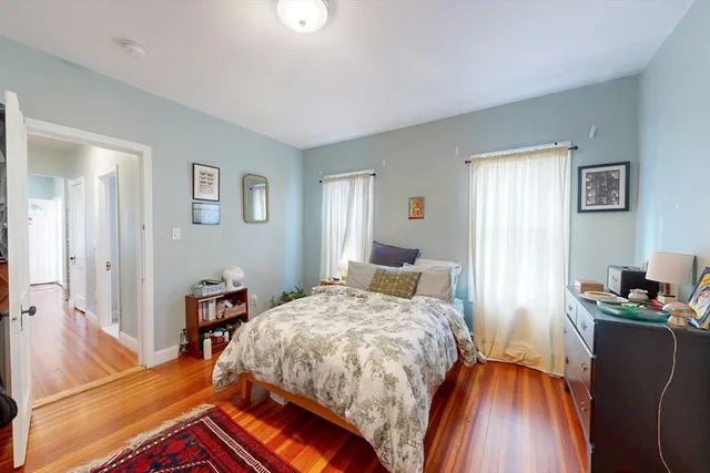 a bedroom with a bed and a computer on a desk next to a window