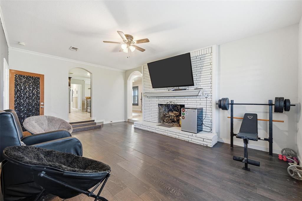 379 Private Road, Unit 4650 Boyd, TX 76023 - Photo 9 of 40 Living room with wood finished floors, a ceiling fan, a fireplace, arched walkways, and ornamental molding