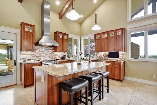 633 Trails End Road Johnson City, TX 78636 - Photo 12 of 29 Warm wood cabinetry and granite countertops anchor this kitchen beneath soaring vaulted ceilings.