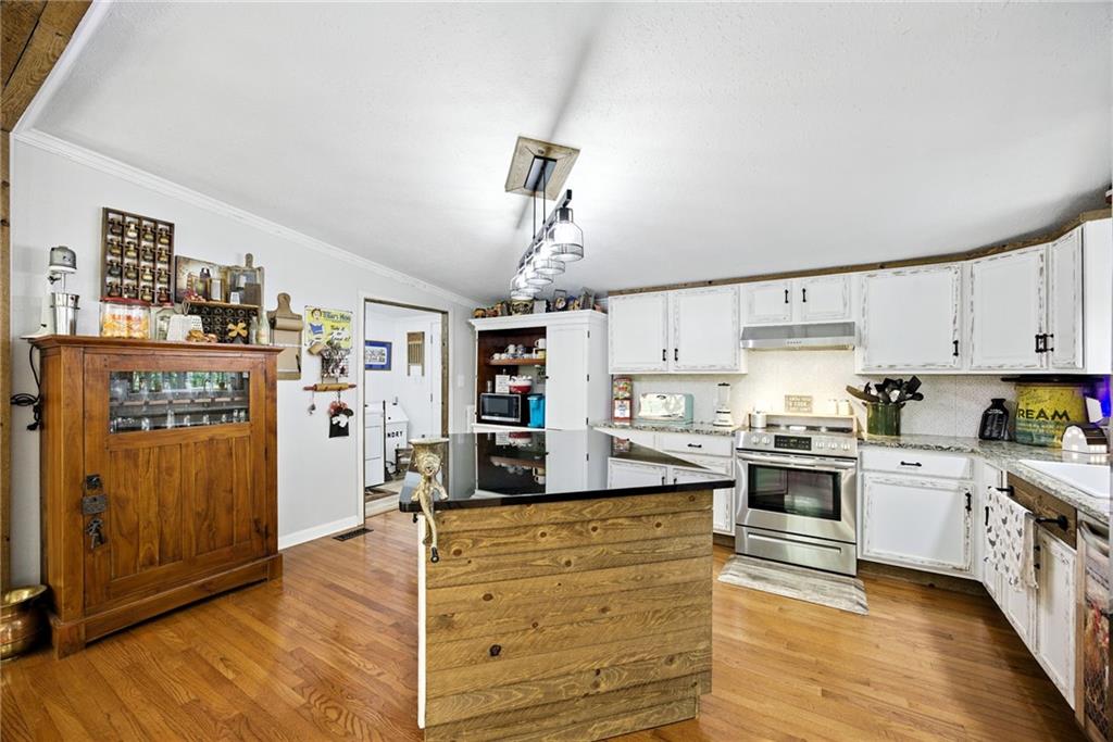731 Borders Road Commerce, GA 30530 - Photo 31 of 75 a kitchen with stainless steel appliances granite countertop a refrigerator a stove oven a sink dishwasher and white cabinets with wooden floor