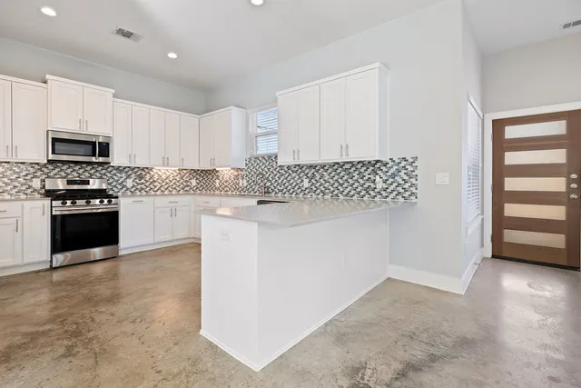 a kitchen with stainless steel appliances granite countertop a stove top oven a sink and a microwave