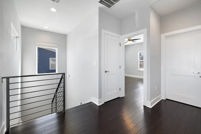 an empty room with wooden floor mirror and windows