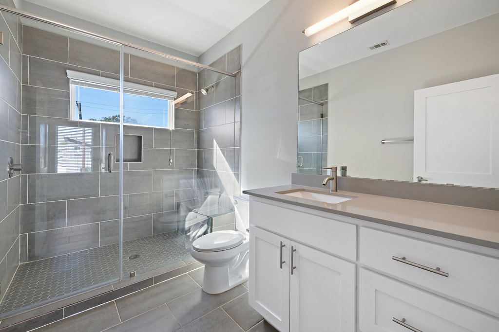 6301 Santos Street, Unit A Austin, TX 78741 - Photo 26 of 37 a bathroom with a granite countertop sink a toilet and shower