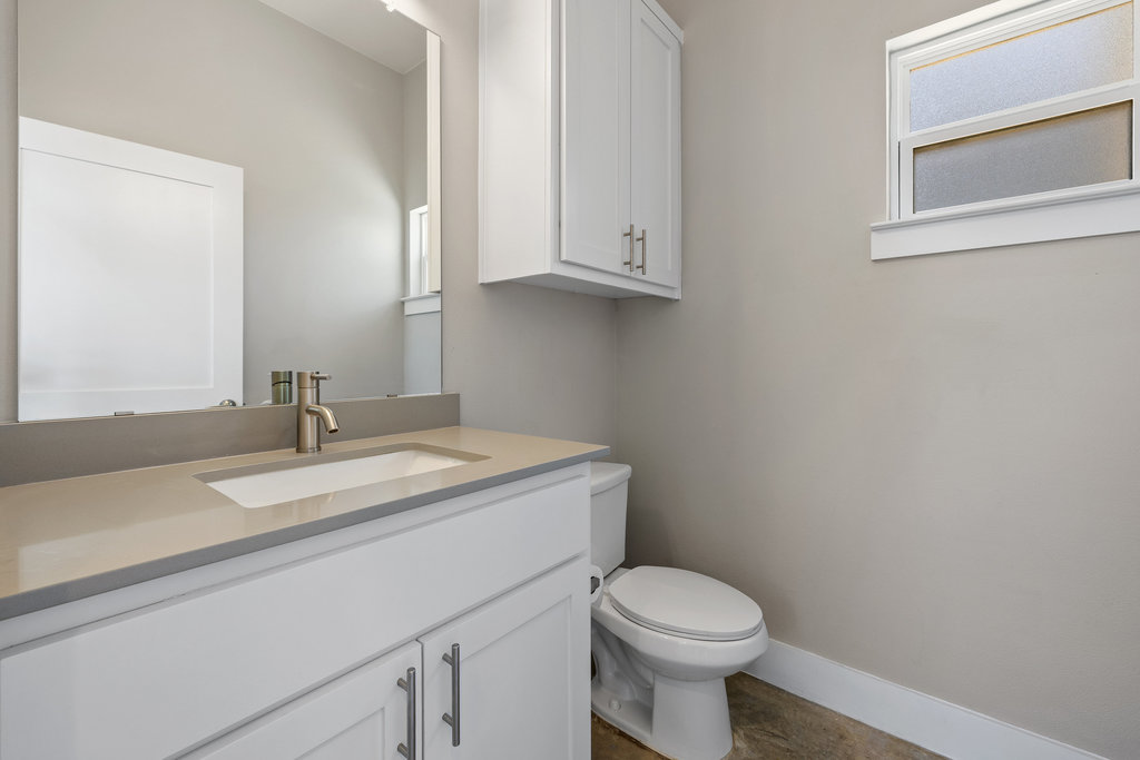 6301 Santos Street, Unit A Austin, TX 78741 - Photo 27 of 37 a bathroom with a granite countertop toilet sink and mirror