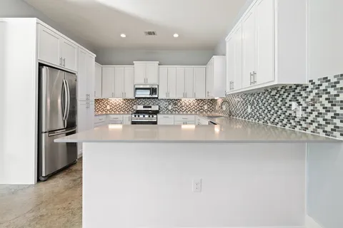 a kitchen with stainless steel appliances a refrigerator sink and white cabinets