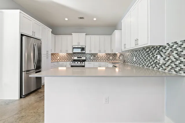 a kitchen with stainless steel appliances a refrigerator sink and white cabinets