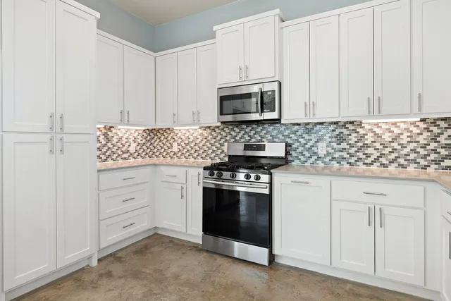 a kitchen with white cabinets and stainless steel appliances