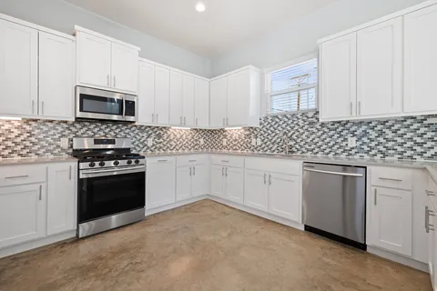 a kitchen with granite countertop white cabinets and stainless steel appliances