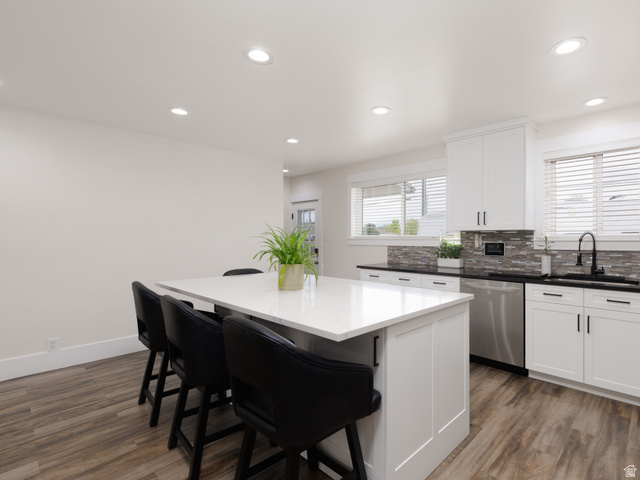 8252 Wood Street Midvale, UT 84047 - Photo 6 of 40 Kitchen featuring a quartz-topped island, white cabinetry, stainless steel appliances, a textured tile backsplash, and wood-finish flooring