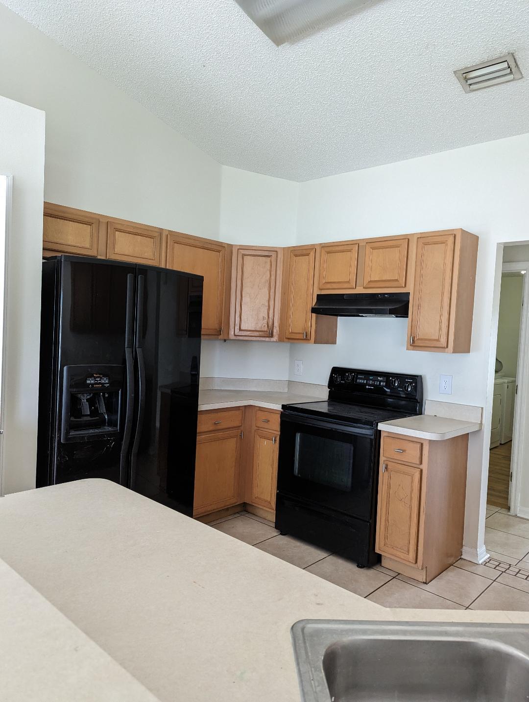 3486 Southwest San Benito Street Port St. Lucie, FL 34953 - Photo 2 of 4 a kitchen with stainless steel appliances kitchen island granite countertop a refrigerator stove and sink