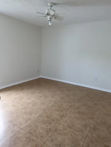 an empty room with a ceiling fan and carpet
