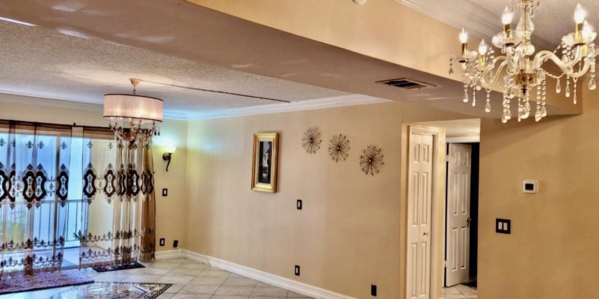610 Northwest 13th Street, Unit 23 Boca Raton, FL 33486 - Photo 27 of 28 a view of a hallway with a dining room and chandelier
