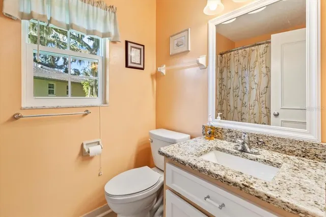 a bathroom with a granite countertop sink a toilet and a mirror