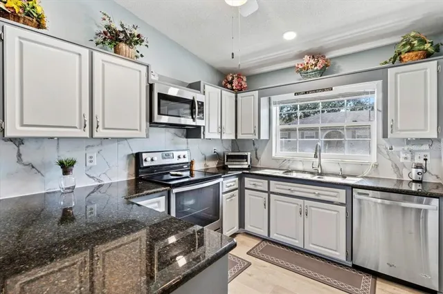 a kitchen with stainless steel appliances granite countertop a sink and cabinets