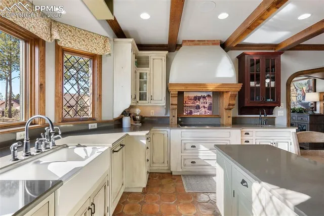 a large kitchen with stainless steel appliances a large counter top a stove a sink and a large window