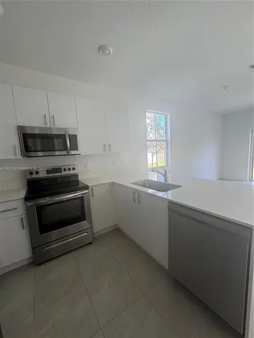 a kitchen with a stove a microwave and window
