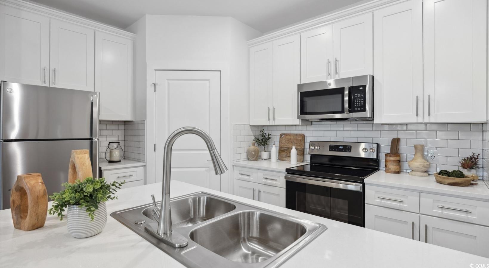 31 Quaker Rdg Drive, Unit MEANDER Carolina Shores, NC 28467 - Photo 20 of 38 Kitchen featuring appliances with stainless steel finishes, light countertops, white cabinetry, and tasteful backsplash