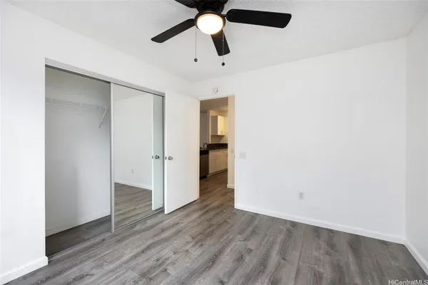 an empty room with wooden floor ceiling fan and window