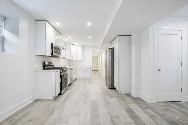 a kitchen with a refrigerator a stove top oven and white cabinets