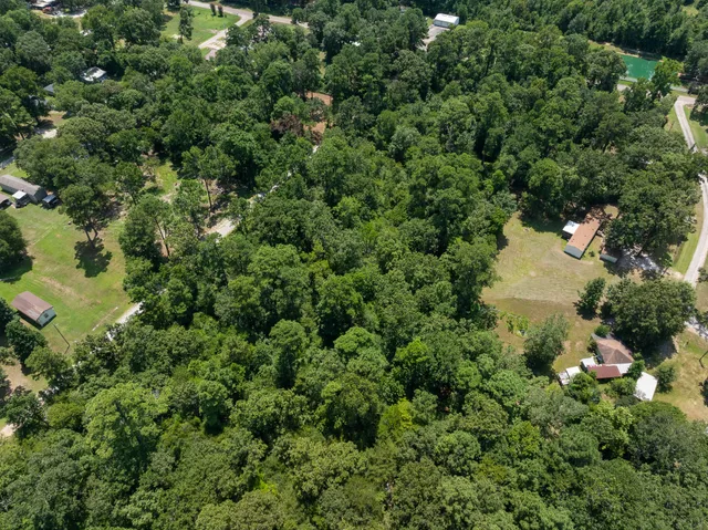 an aerial view of residential house with outdoor space and trees all around