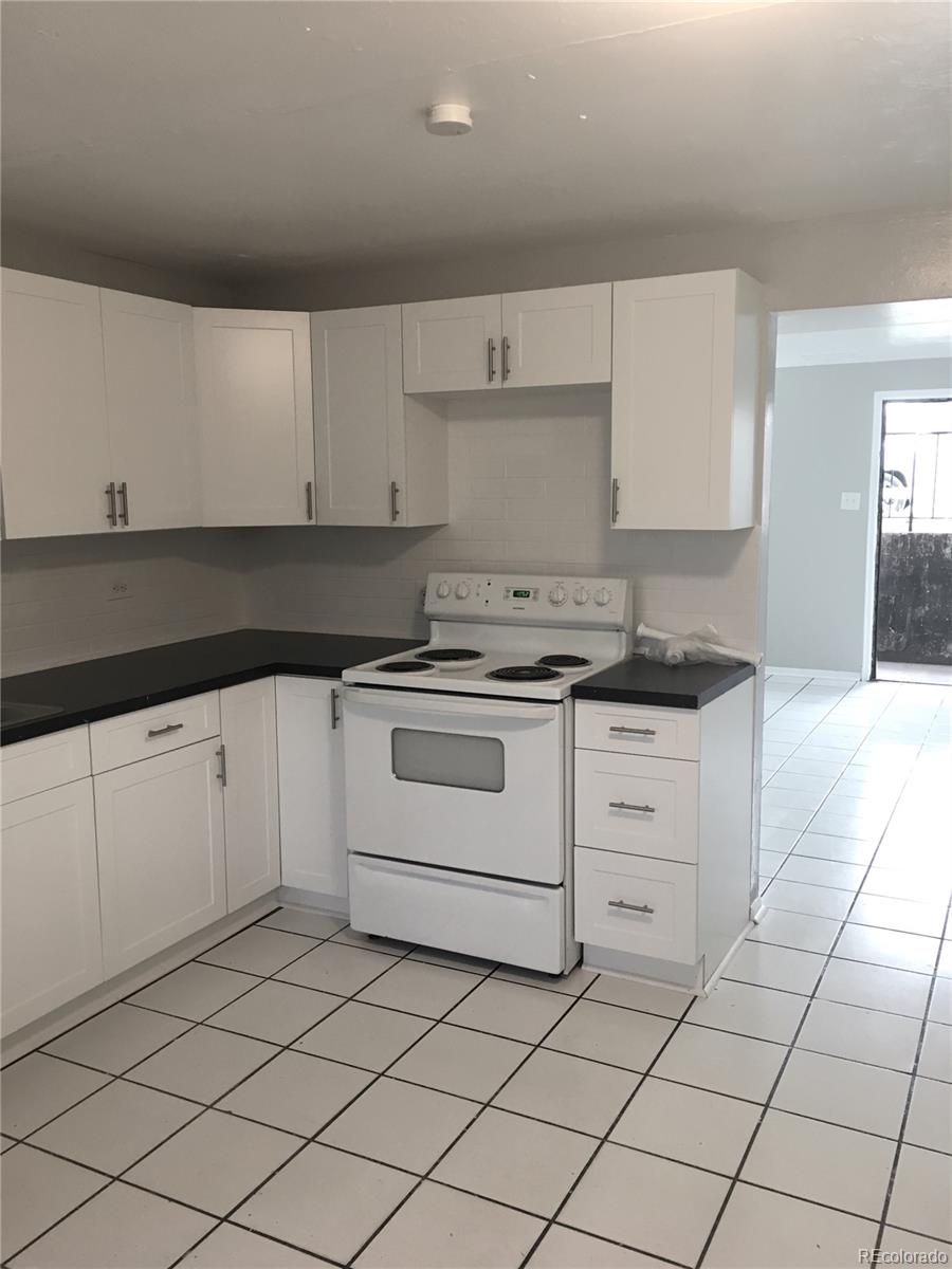7111 Raleigh Street Westminster, CO 80030 - Photo 23 of 38 a kitchen with granite countertop white cabinets and white appliances