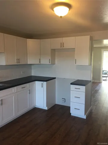 a kitchen with granite countertop white cabinets and a wooden floor