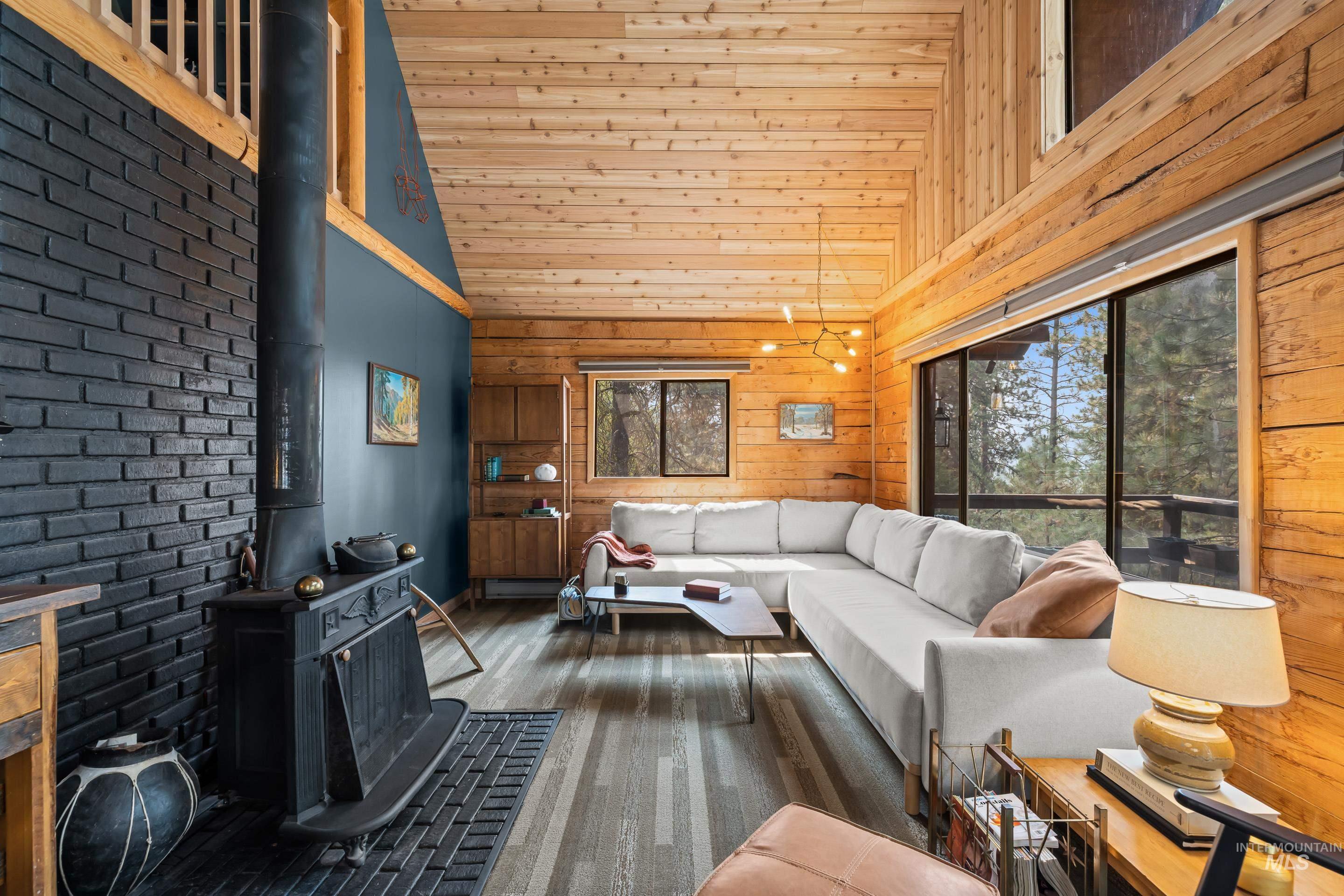 73 Rainbow Ridge Road Garden Valley, ID 83622 - Photo 22 of 49 Wood-paneled vaulted ceiling, exposed wood beams, and a black brick accent wall with a wood-burning stove