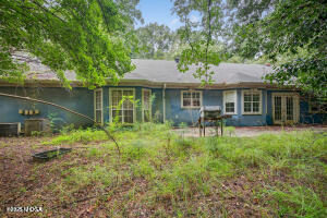a backyard of a house with table and chairs potted plants and large tree