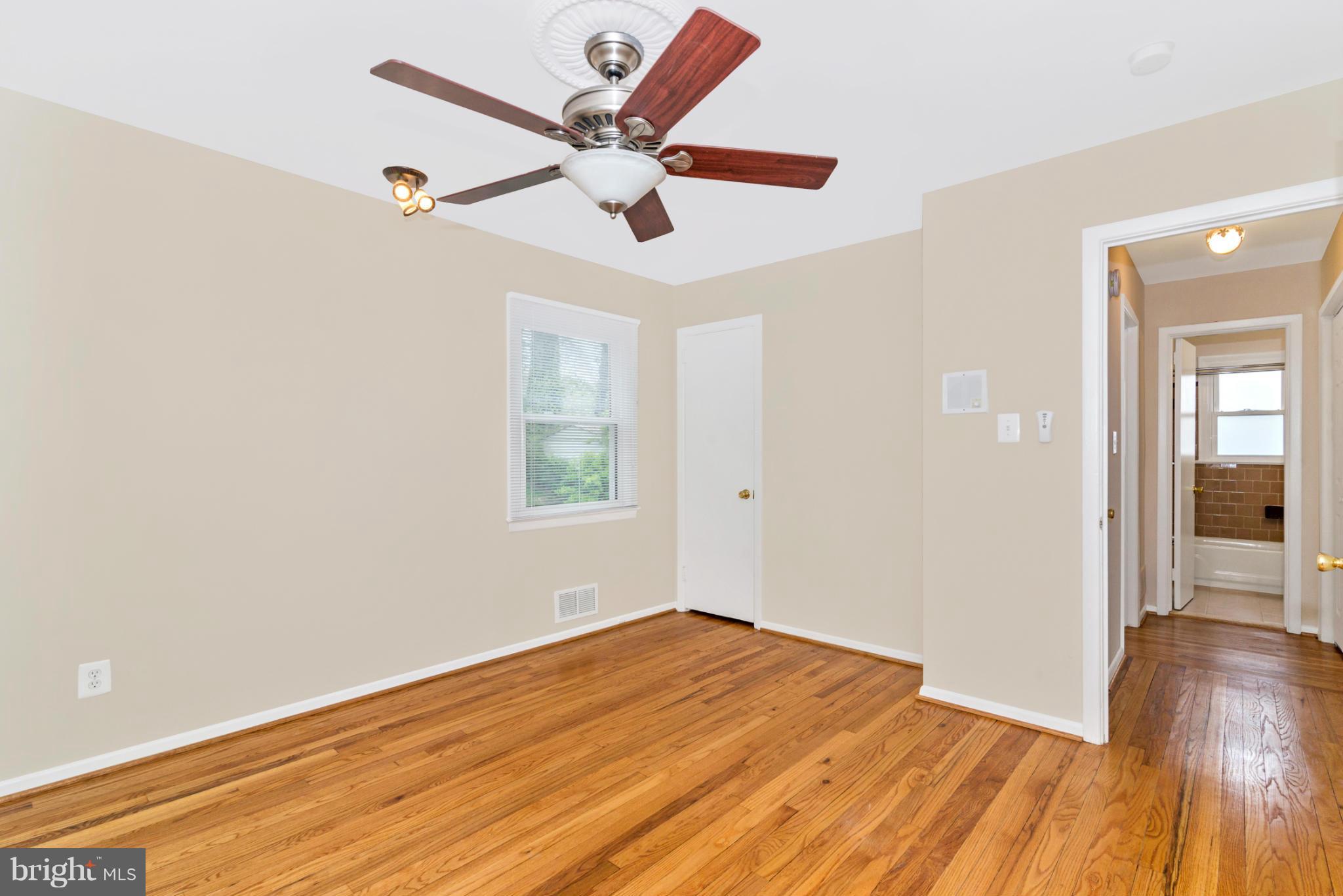 2801 Weisman Road Silver Spring, MD 20902 - Photo 10 of 30 an empty room with wooden floor fan and windows