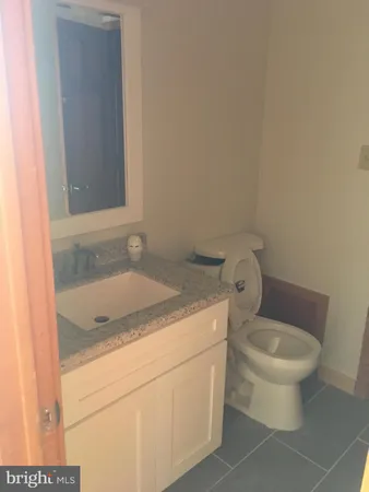 a bathroom with a granite countertop sink and a toilet