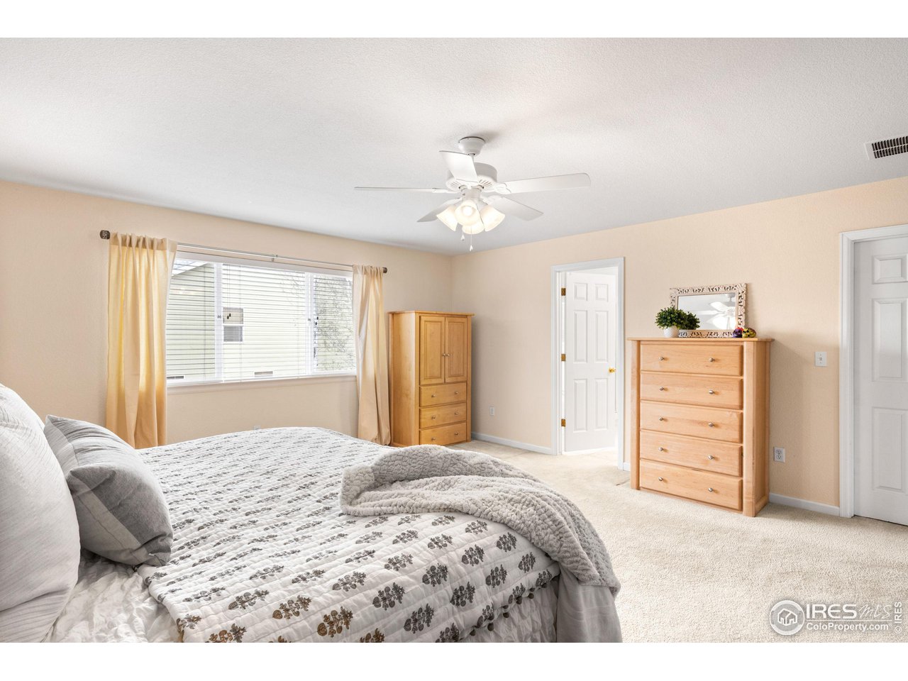 5861 Mountain Shadows Boulevard Firestone, CO 80504 - Photo 21 of 39 a bedroom with a bed a dresser and a chandelier