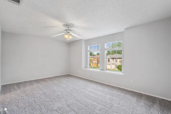 an empty room with windows and ceiling fan