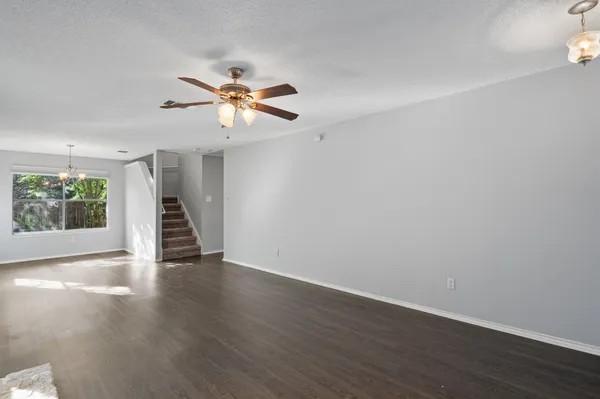a view of an empty room with wooden floor ceiling fan and a window
