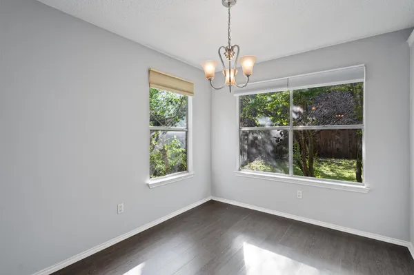 a view of an empty room with wooden floor windows and a chandelier