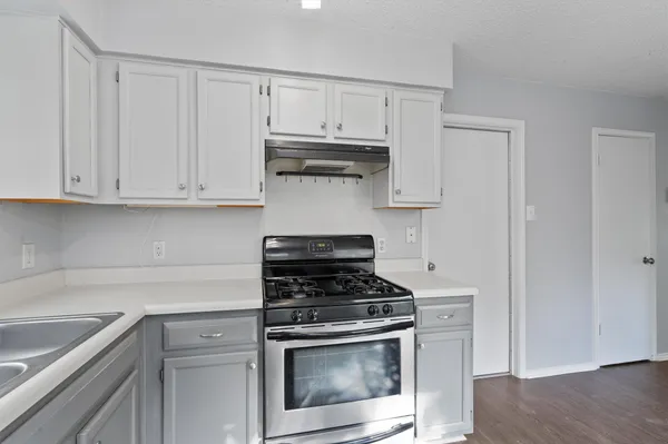 a kitchen with granite countertop white cabinets and stainless steel appliances
