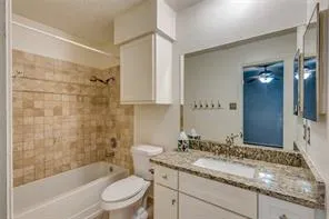 a bathroom with a granite countertop sink a toilet and shower