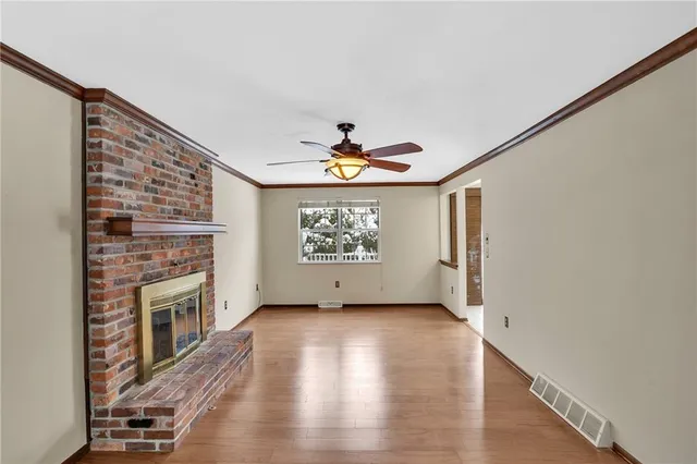 a view of an empty room with a fireplace and wooden floor