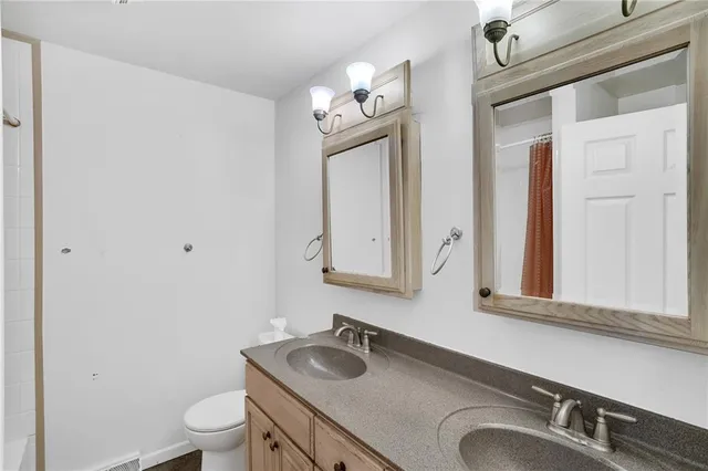 a bathroom with a granite countertop sink vanity mirror and toilet