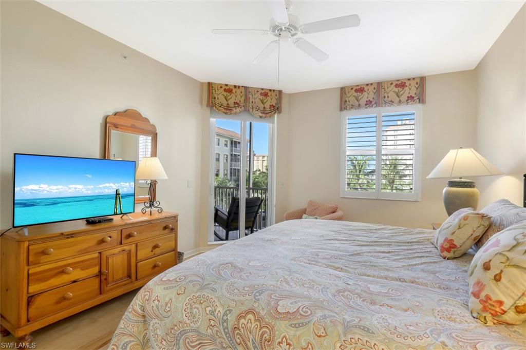 460 Launch Circle, Unit 403 Naples, FL 34108 - Photo 13 of 34 a bedroom with a bed and a flat tv screen on dresser