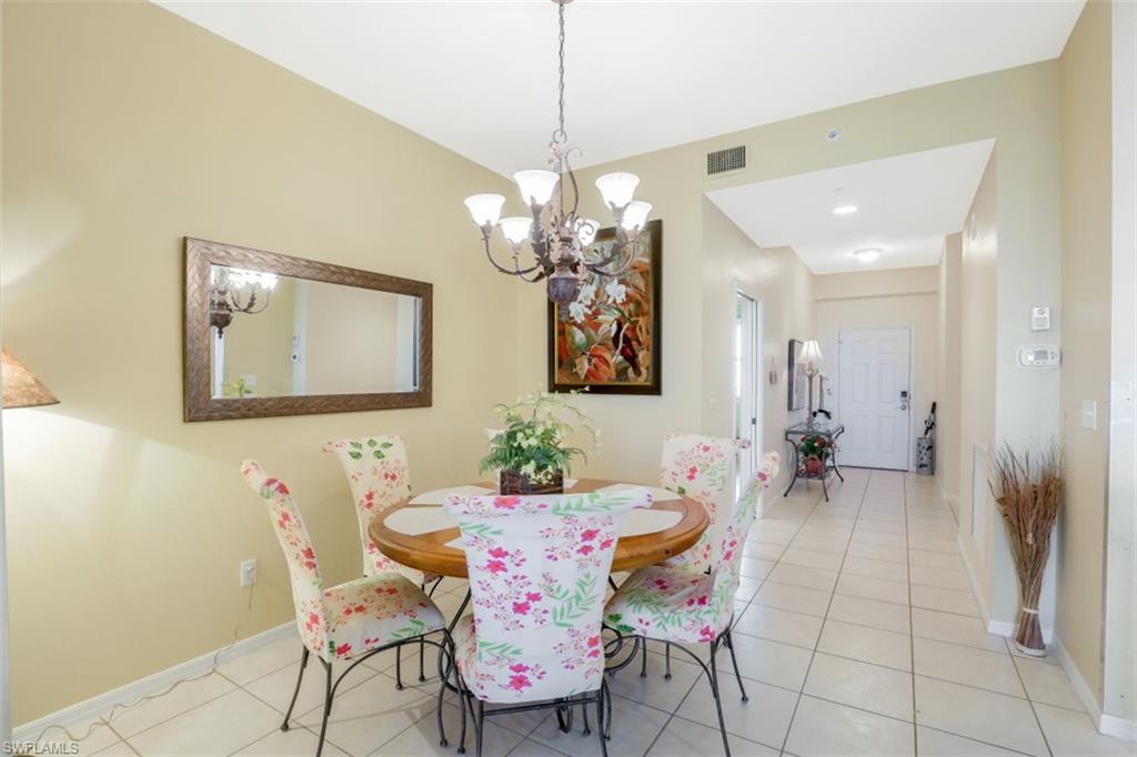 460 Launch Circle, Unit 403 Naples, FL 34108 - Photo 6 of 34 a dining room with chandelier and wooden floor