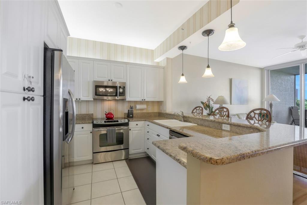 460 Launch Circle, Unit 403 Naples, FL 34108 - Photo 8 of 34 a kitchen with a sink dishwasher a stove and a refrigerator with wooden floor