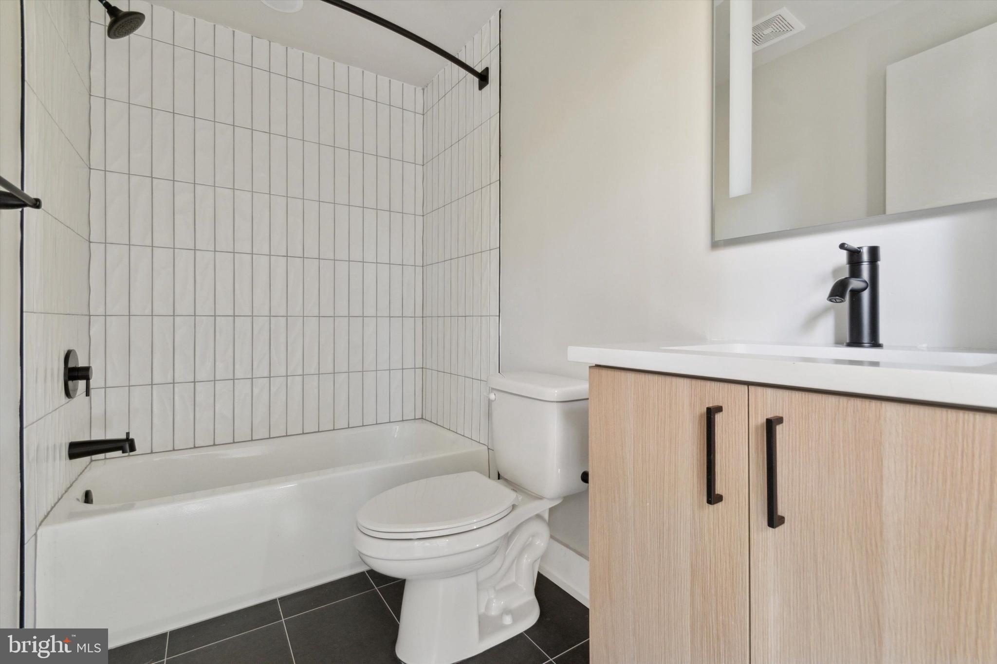 5521 Wayne Avenue, Unit 207 Philadelphia, PA 19144 - Photo 12 of 16 a bathroom with a toilet a sink a mirror and bathtub