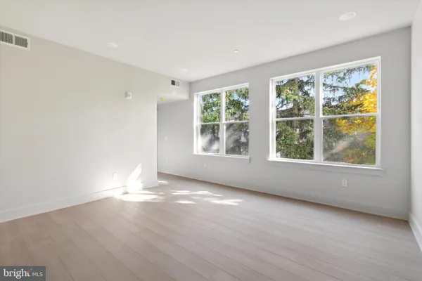 an empty room with wooden floor and windows