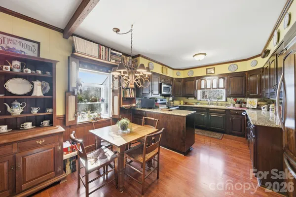 a dining room with stainless steel appliances granite countertop a dining table chairs a refrigerator and kitchen view