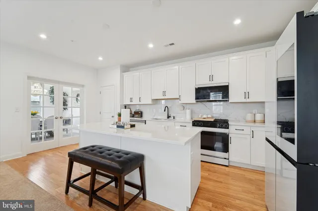 a kitchen with stainless steel appliances a stove a sink a microwave a refrigerator and cabinets