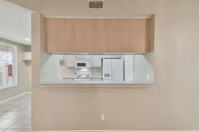 a view of a big room with a chandelier fan and windows