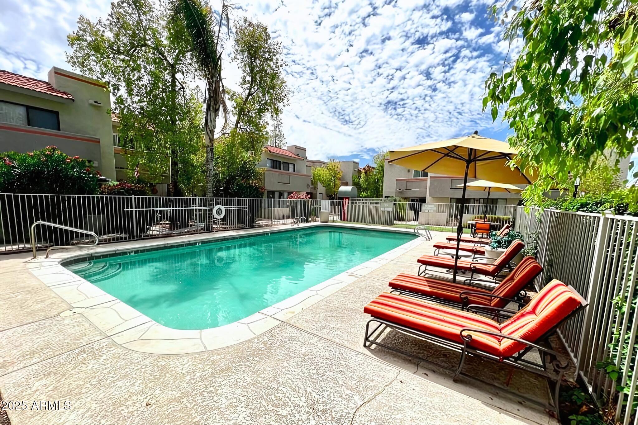 885 North Granite Reef Road, Unit 63 Scottsdale, AZ 85257 - Photo 20 of 23 a view of a swimming pool with a bench and trees in the background