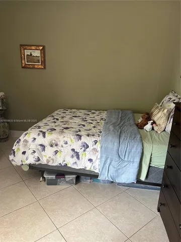 a bedroom with a bed and a lamp on dresser