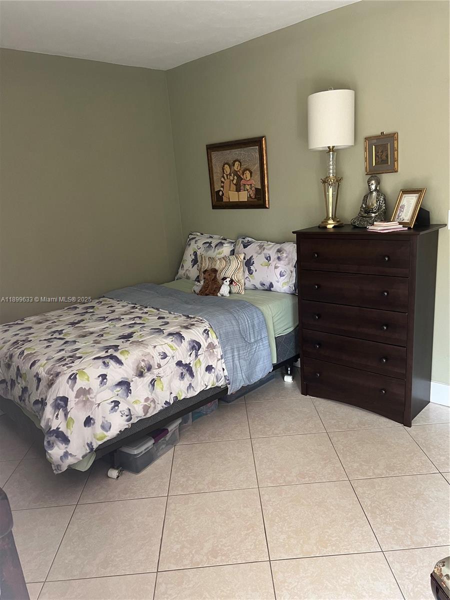 8335 Southwest 72nd Avenue, Unit 212D Miami, FL 33143 - Photo 17 of 31 a bedroom with a bed and a lamp on dresser